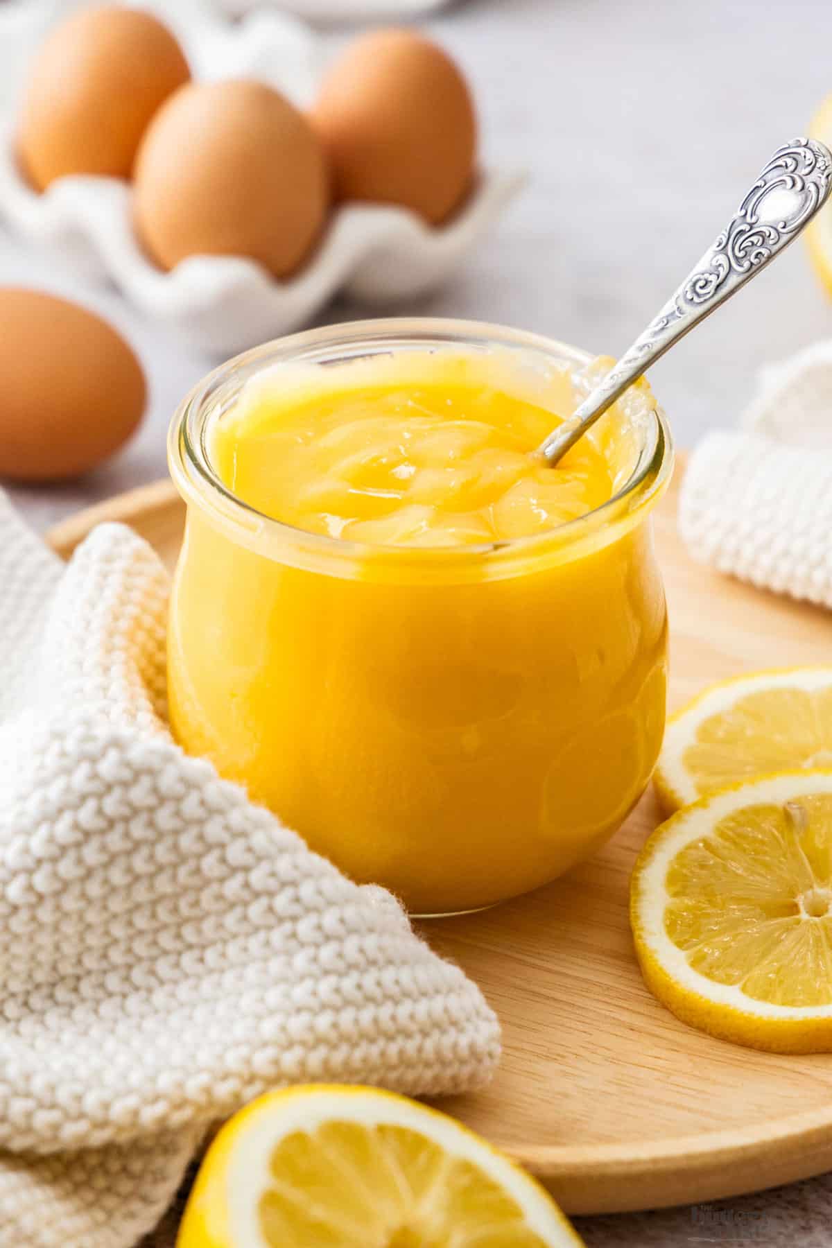A jar of lemon curd with a spoon sticking out.