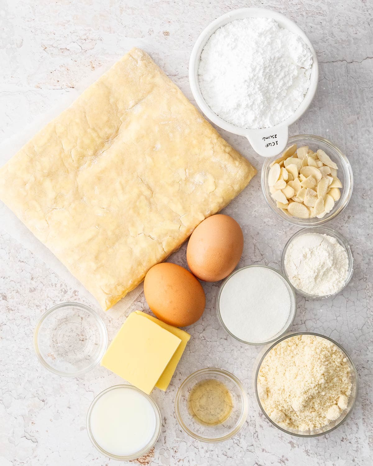 Ingredients for almond Danish braid on a stone surface.