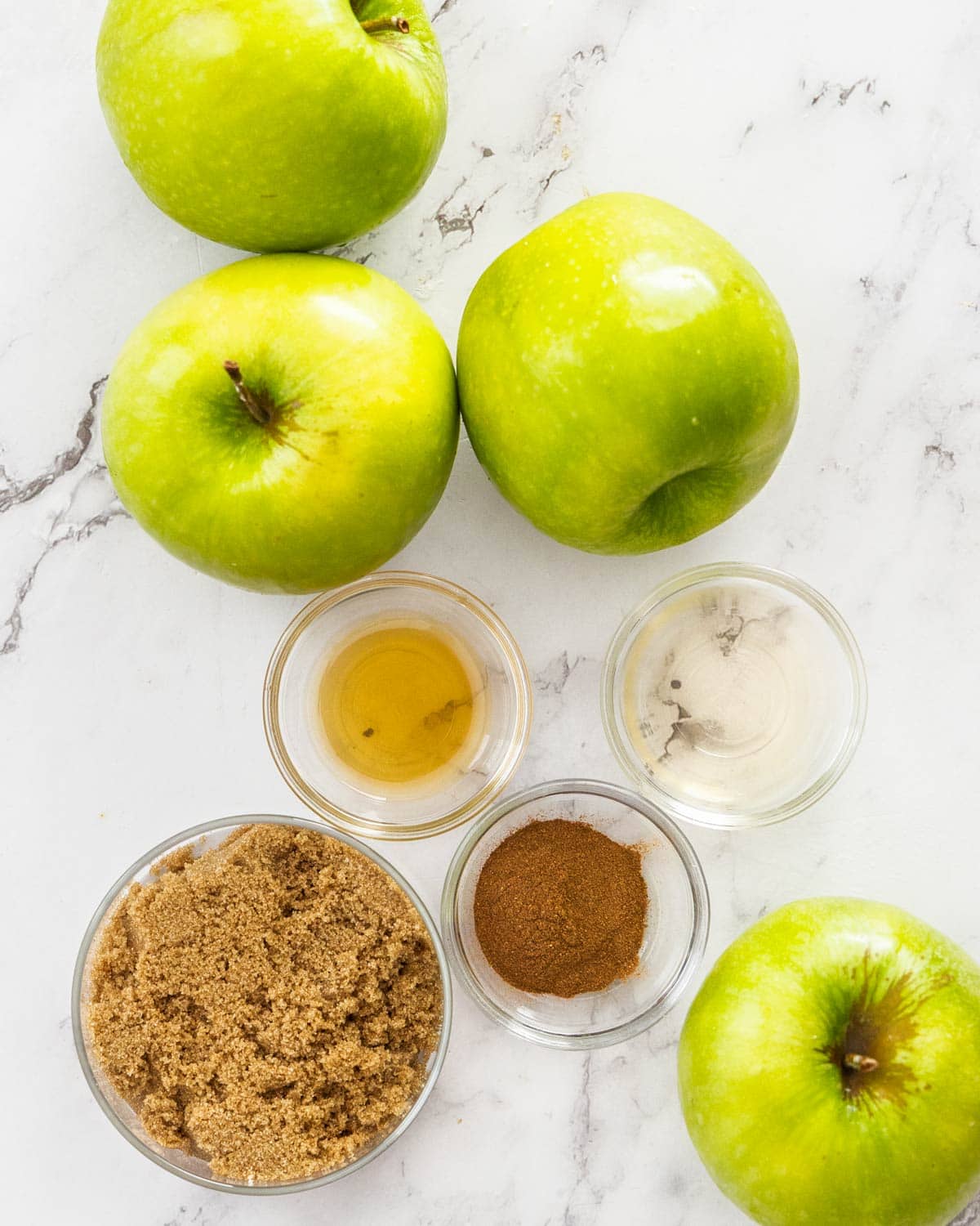 Ingredients for apple compote on a marble surface.