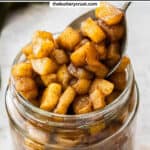 Apple compote being spooned into a jar.