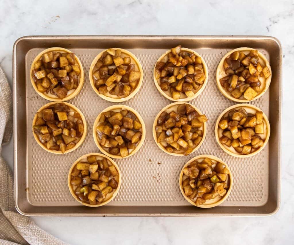 10 pastry tart shells filled with pastry cream and apple compote.
