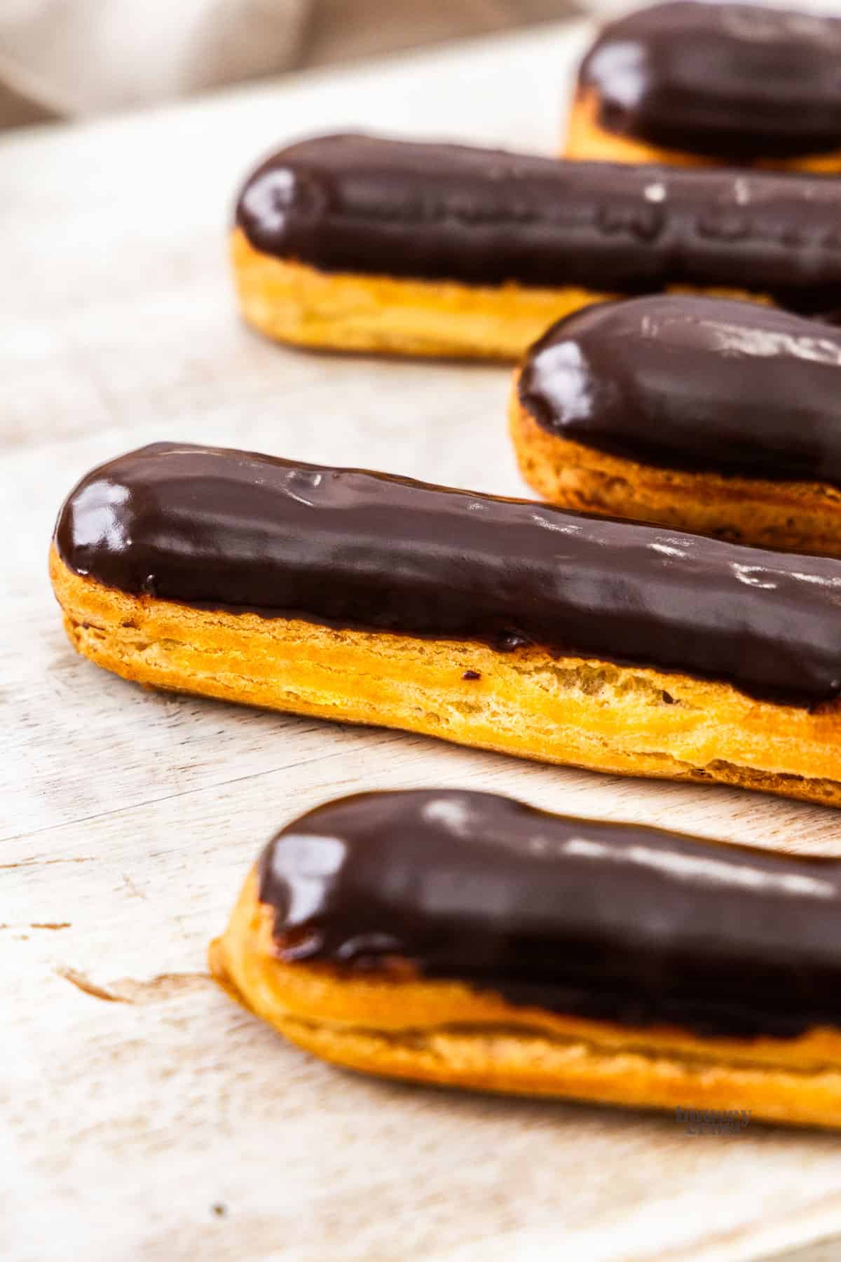 A row of eclairs topped with chocolate glaze.