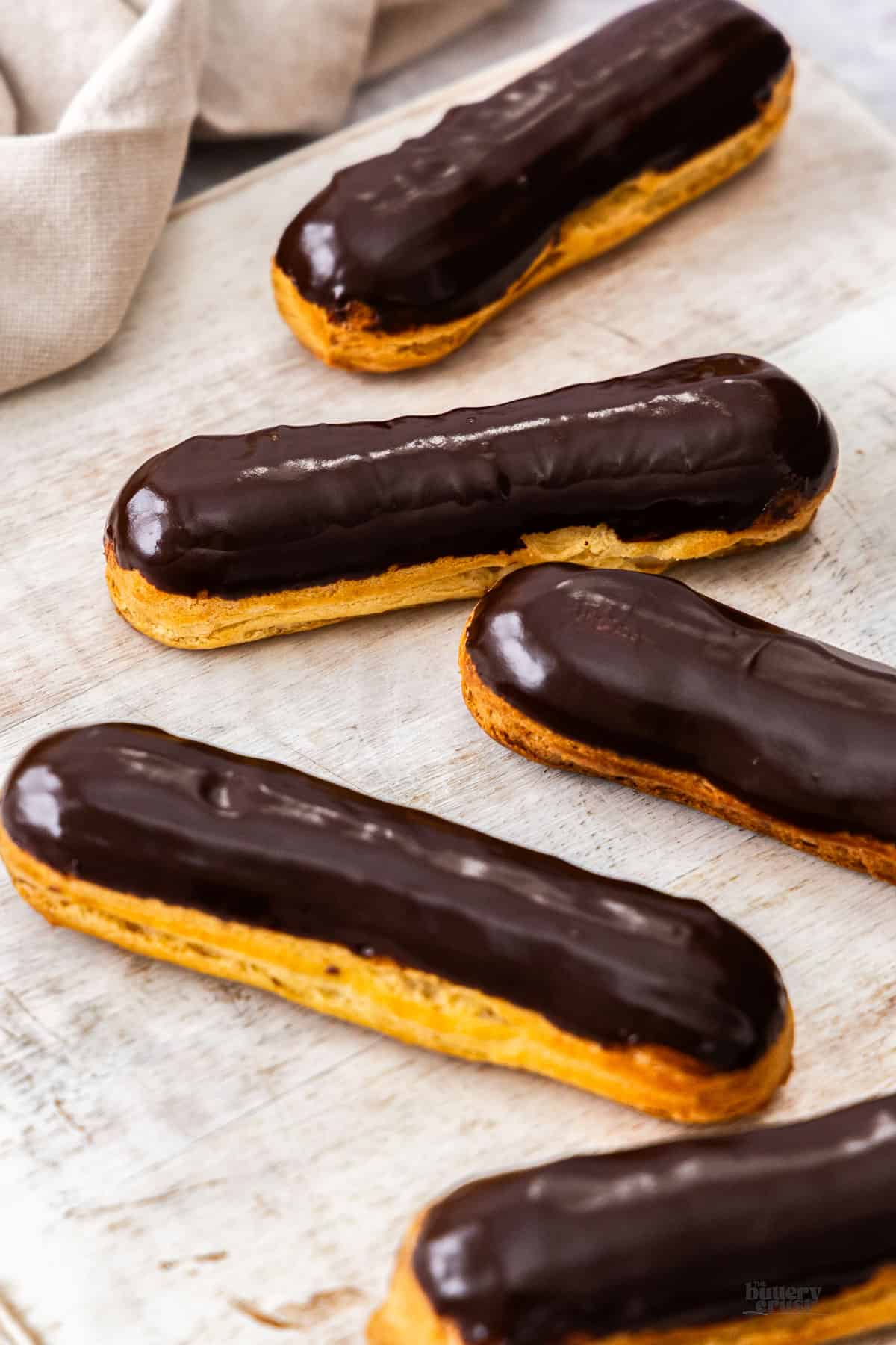 A batch of chocolate eclairs with a shiny chocolate glaze on top.