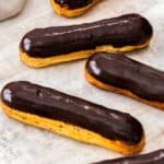 Three eclairs topped with a shiny chocolate glaze.
