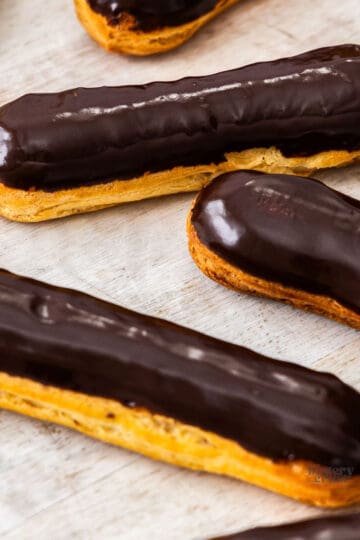 Three eclairs topped with a shiny chocolate glaze.