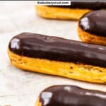 A row of eclairs topped with shiny chocolate glaze.