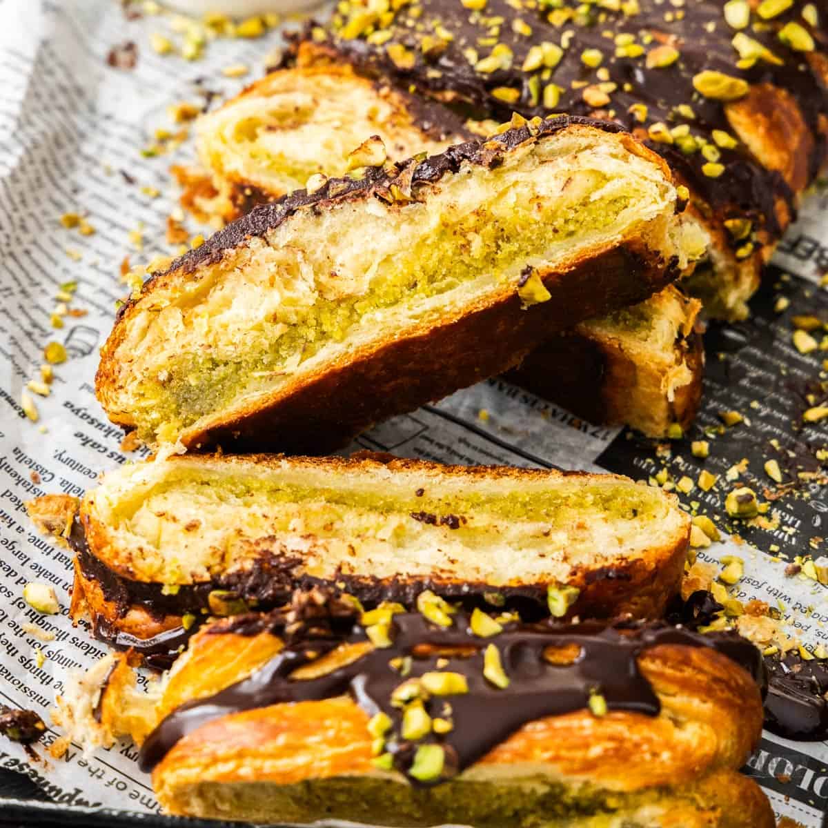 Top down view of a chocolate pistachio Danish braid cut into pieces.