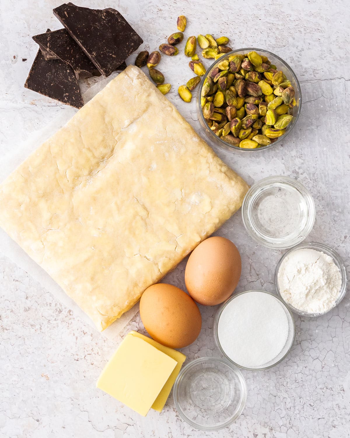 Ingredients for chocolate pistachio Danish braid on a stone surface.