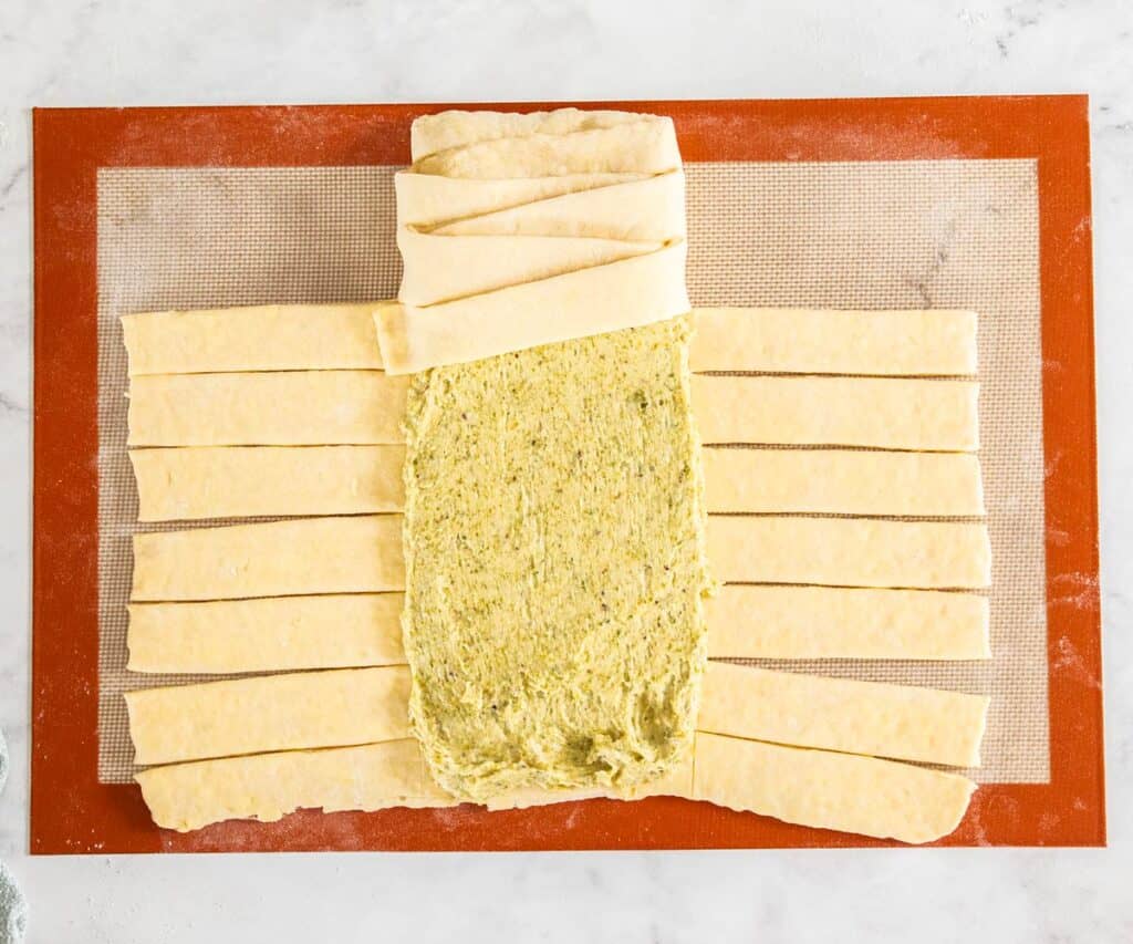 The danish braid dough with the pistachio filling spread over the centre and some of the strips braided.