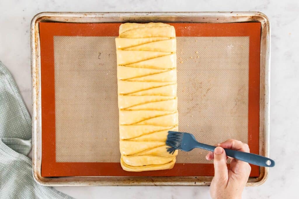 Egg wash being brushed onto the Danish braid.