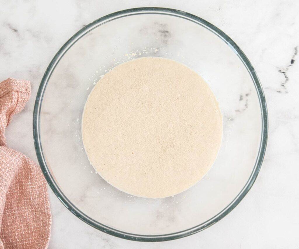 The yeast and milk mixture in a bowl looking puffy.