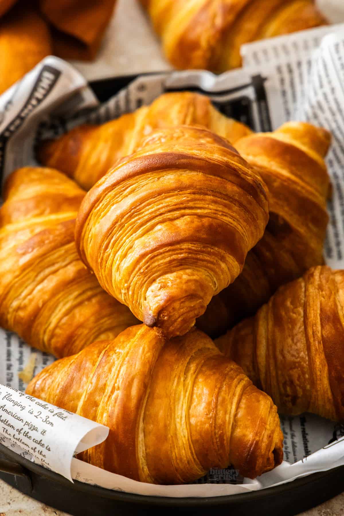 Closeup of a croissant showing the layers, while it sits on top of other croissants.