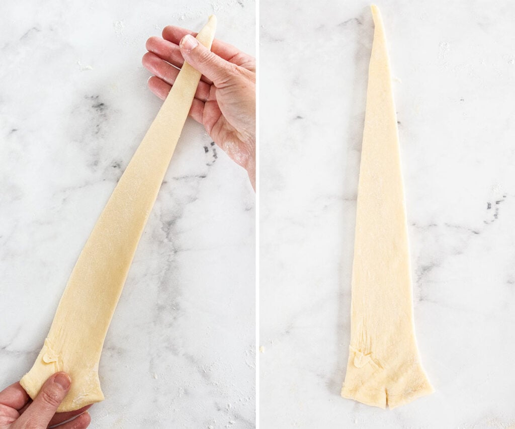 Two hands gently stretching a triangle of dough.