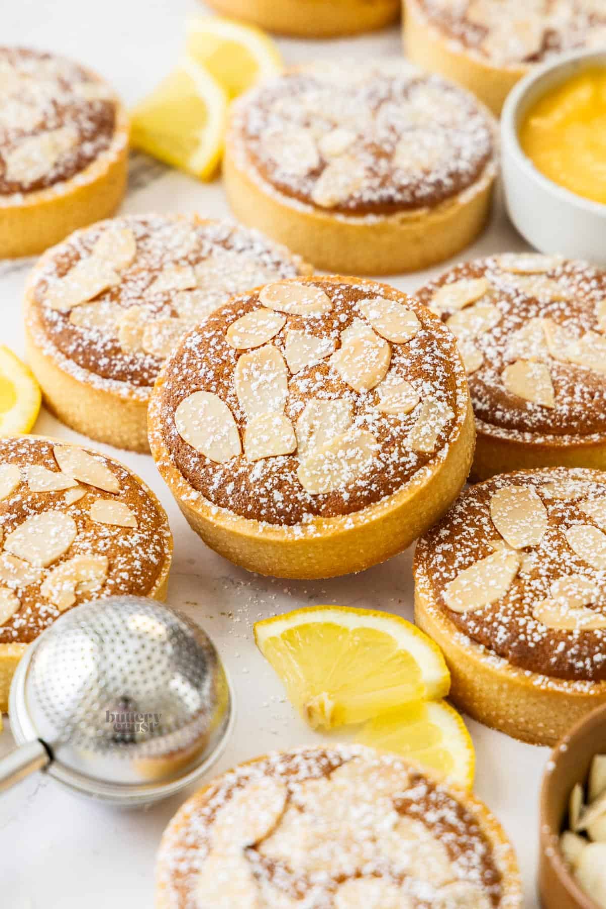 A batch of lemon almond tarts on a marble background.