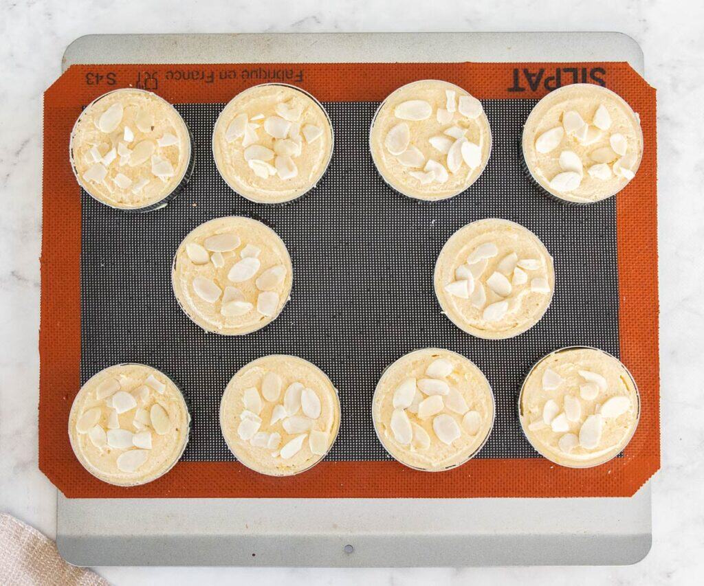 The tarts filled and topped with almonds, ready to bake.