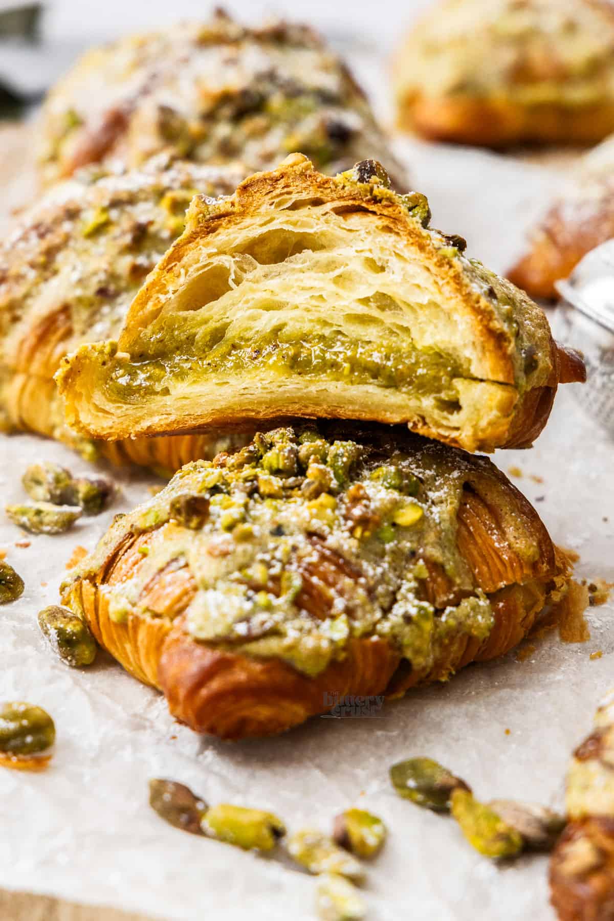 A pistachio croissant cut in half to show the filling inside.