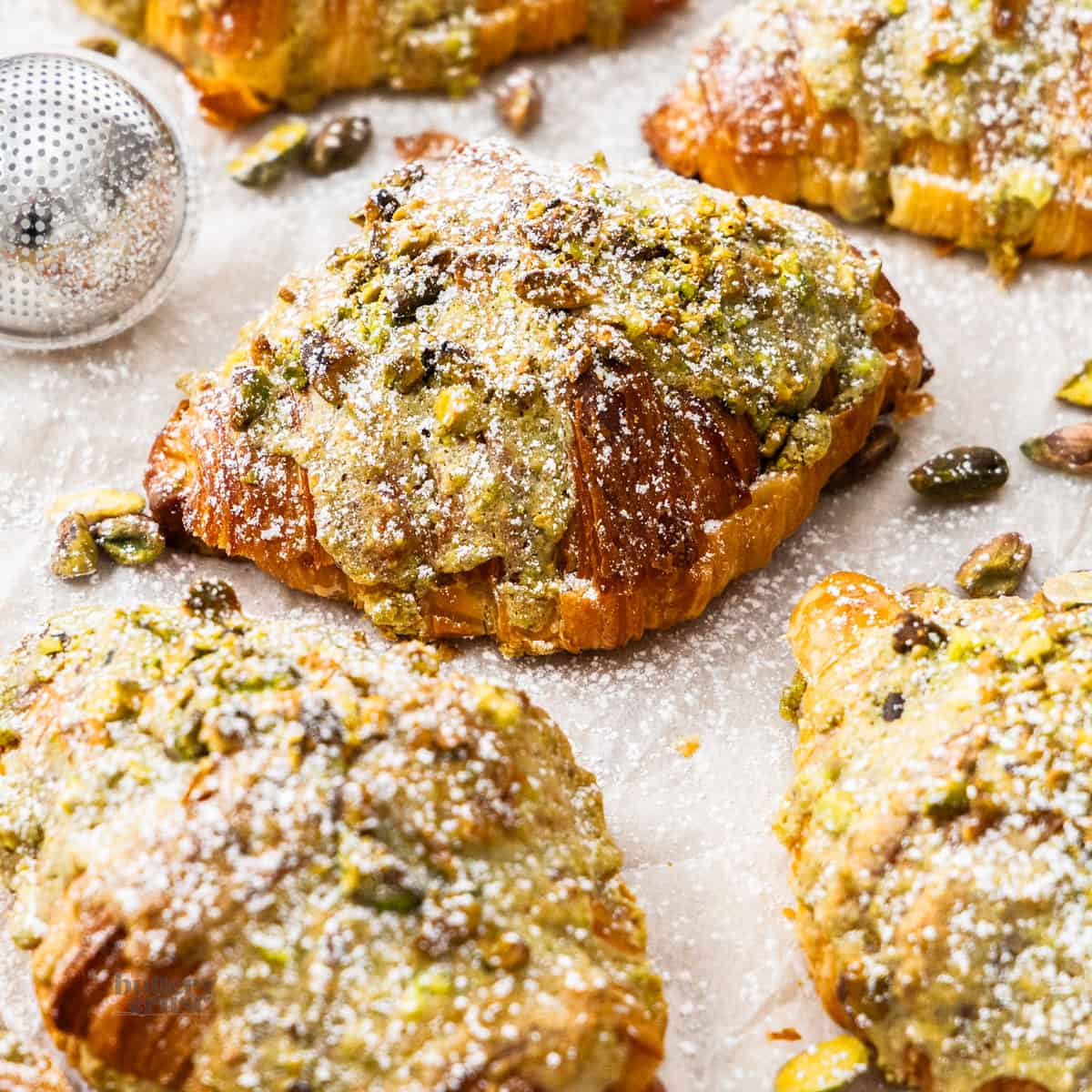 Closeup of a pistachio croissant surrounded by more.