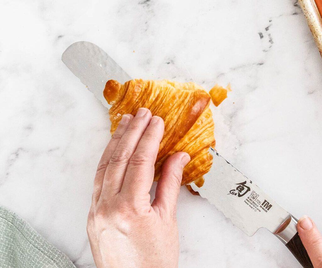 A croissant being sliced in half.