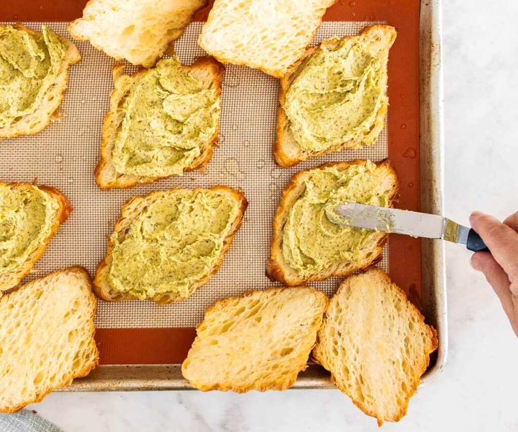 Pistachio frangipane being spread onto the inside of croissants.