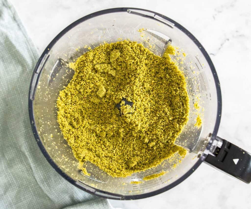 Ground pistachios in a food processor bowl.