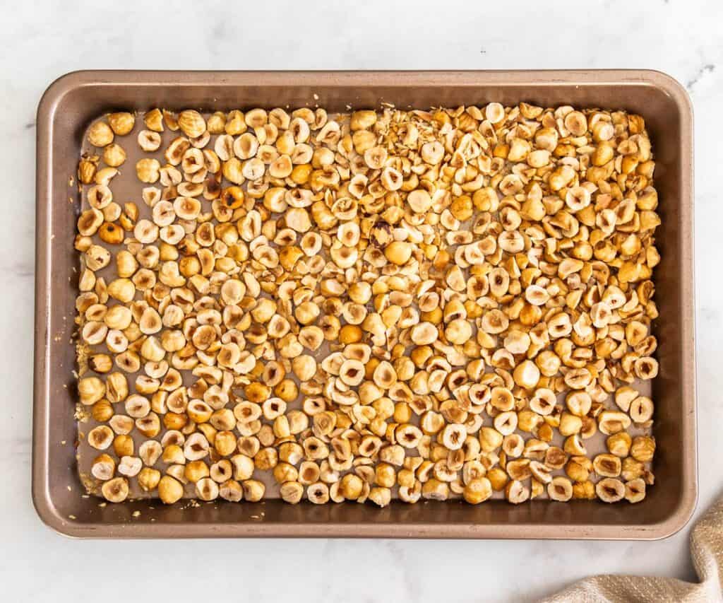 Toasted hazelnuts on a baking tray.
