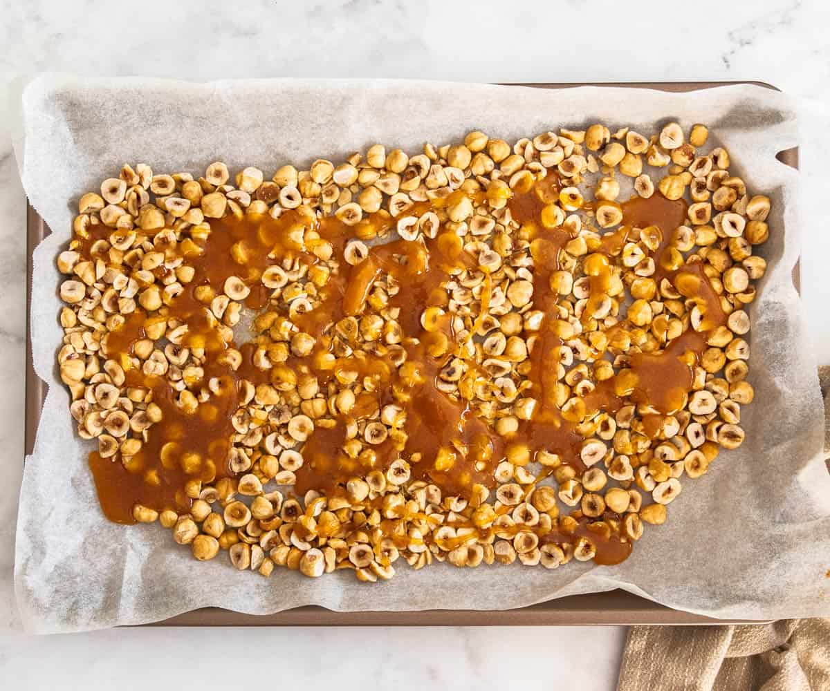 The caramel poured over hazelnuts on a baking tray.