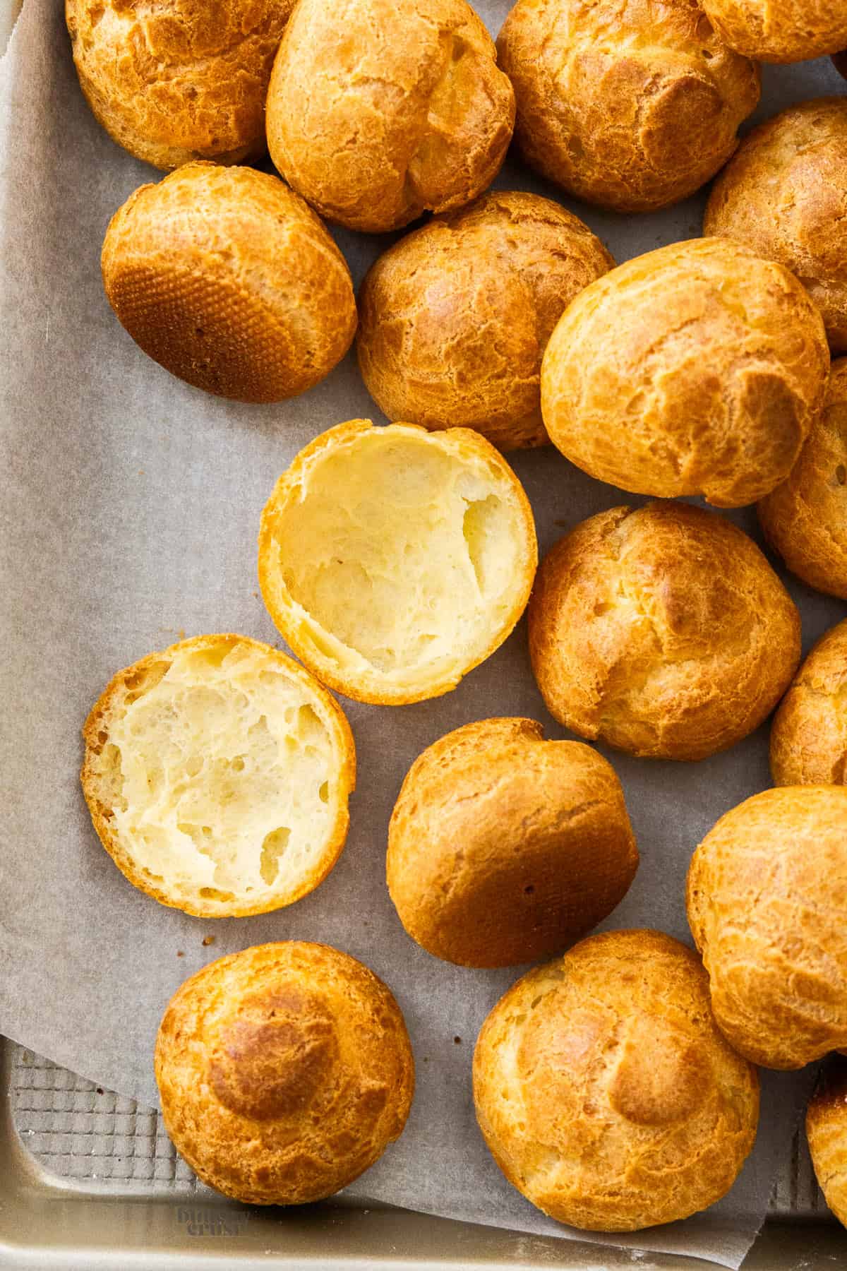A pile of choux buns with one cut open to show the inside texture.