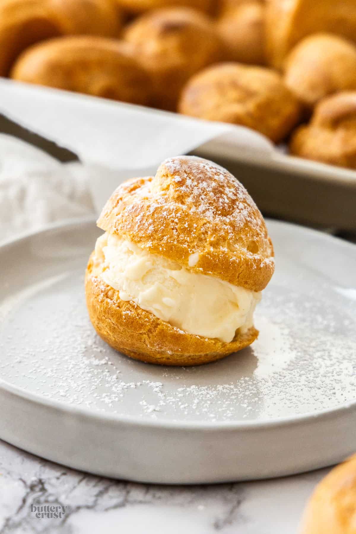 A choux bun filled with ice cream on a dessert plate.