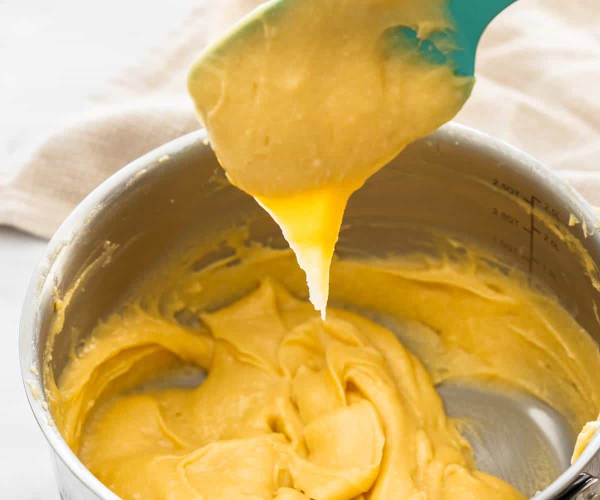 Choux pastry dropping from a spatula in a V shape.