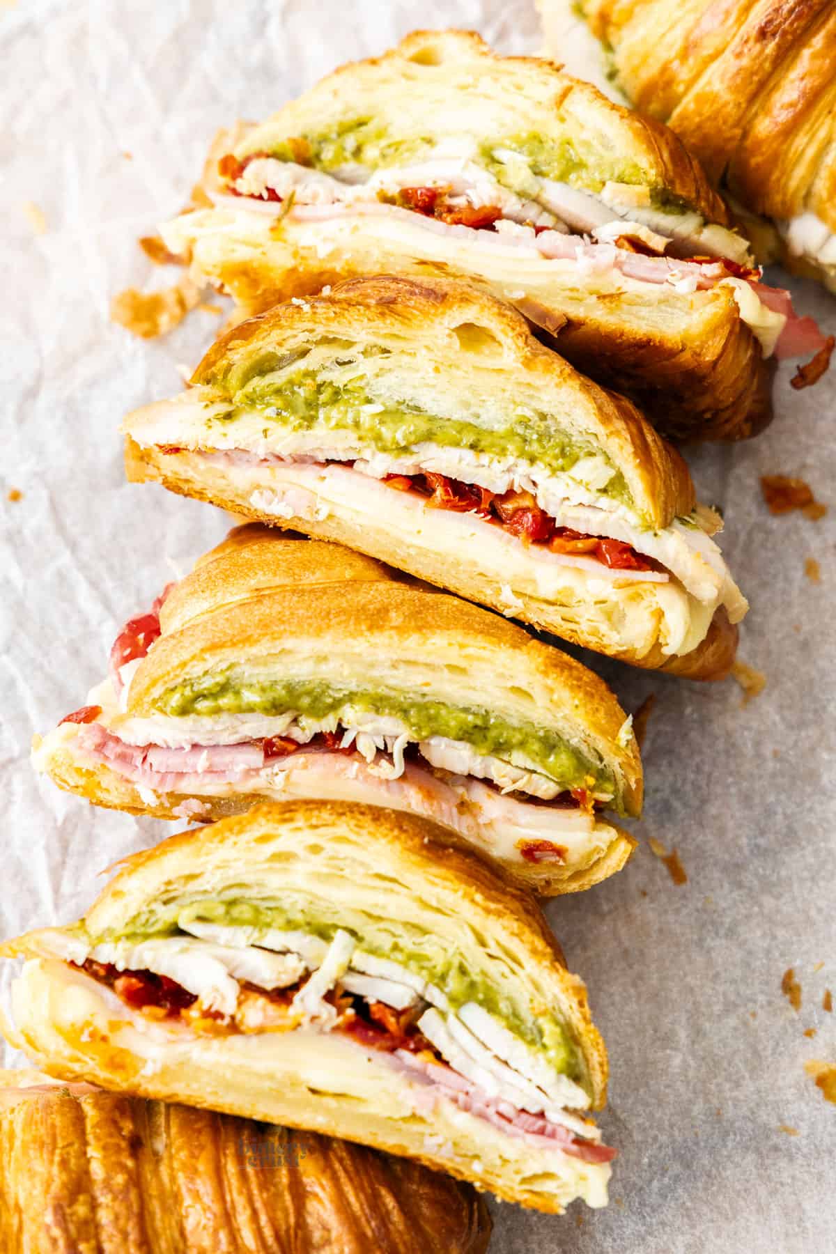 Halves of pesto turkey croissant lined up showing the filling.