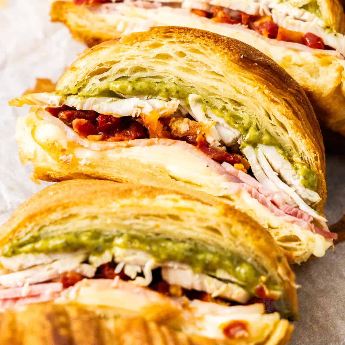 Extreme closeup of the inside of a pesto turkey croissant.