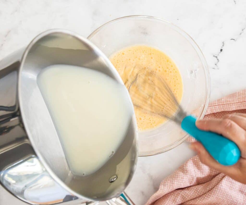 Pouring hot milk into the egg mixture.