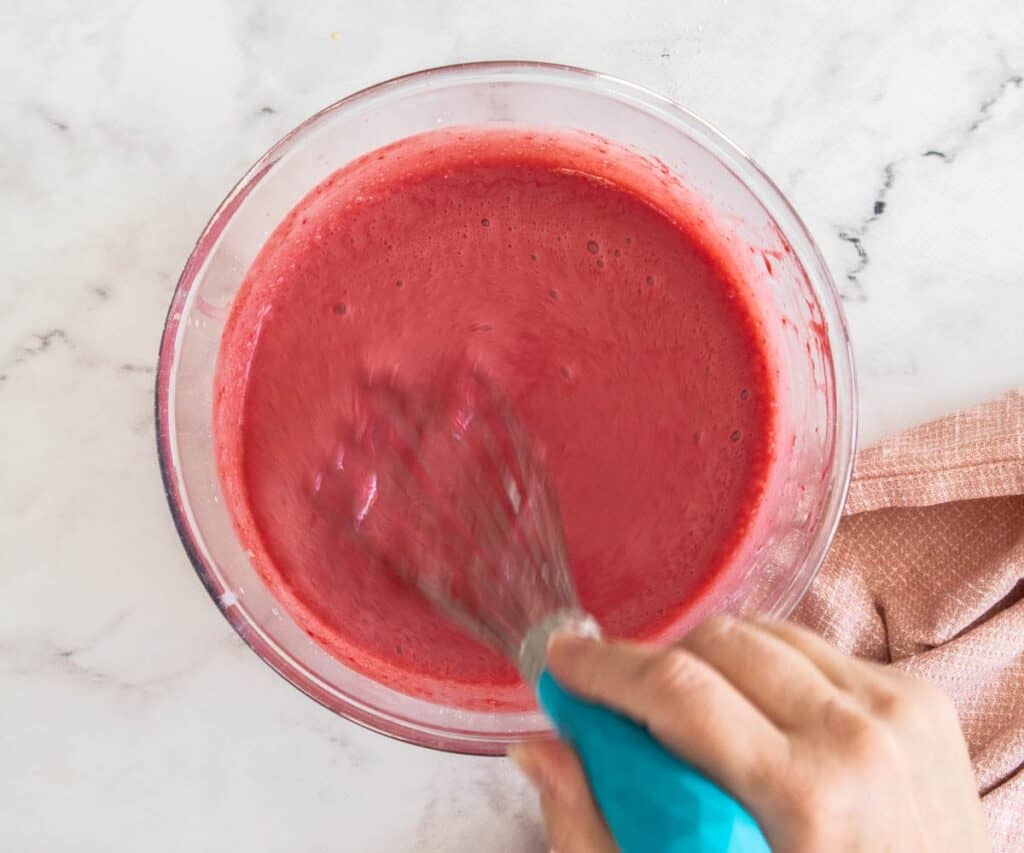 Whisking the raspberry puree into the milk and egg mixture.