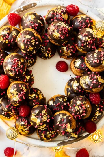 Top down view of a profiterole wreath topped with gold leaf.