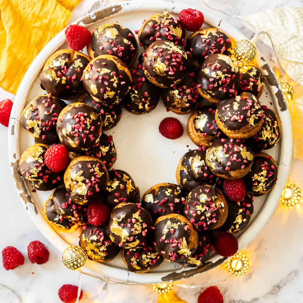 Top down view of a profiterole wreath topped with gold leaf.