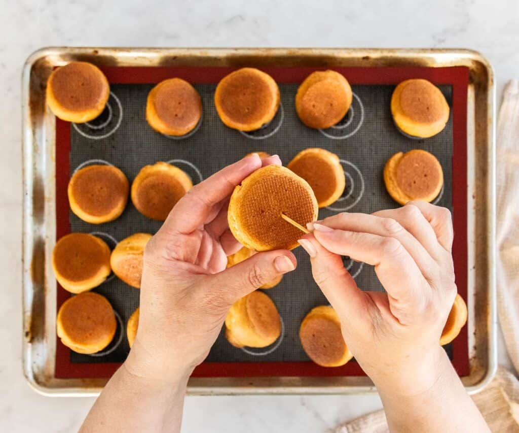 Poking holes in the base of choux buns.