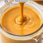 Hazelnut praline paste dribbling off a spoon into a jar.