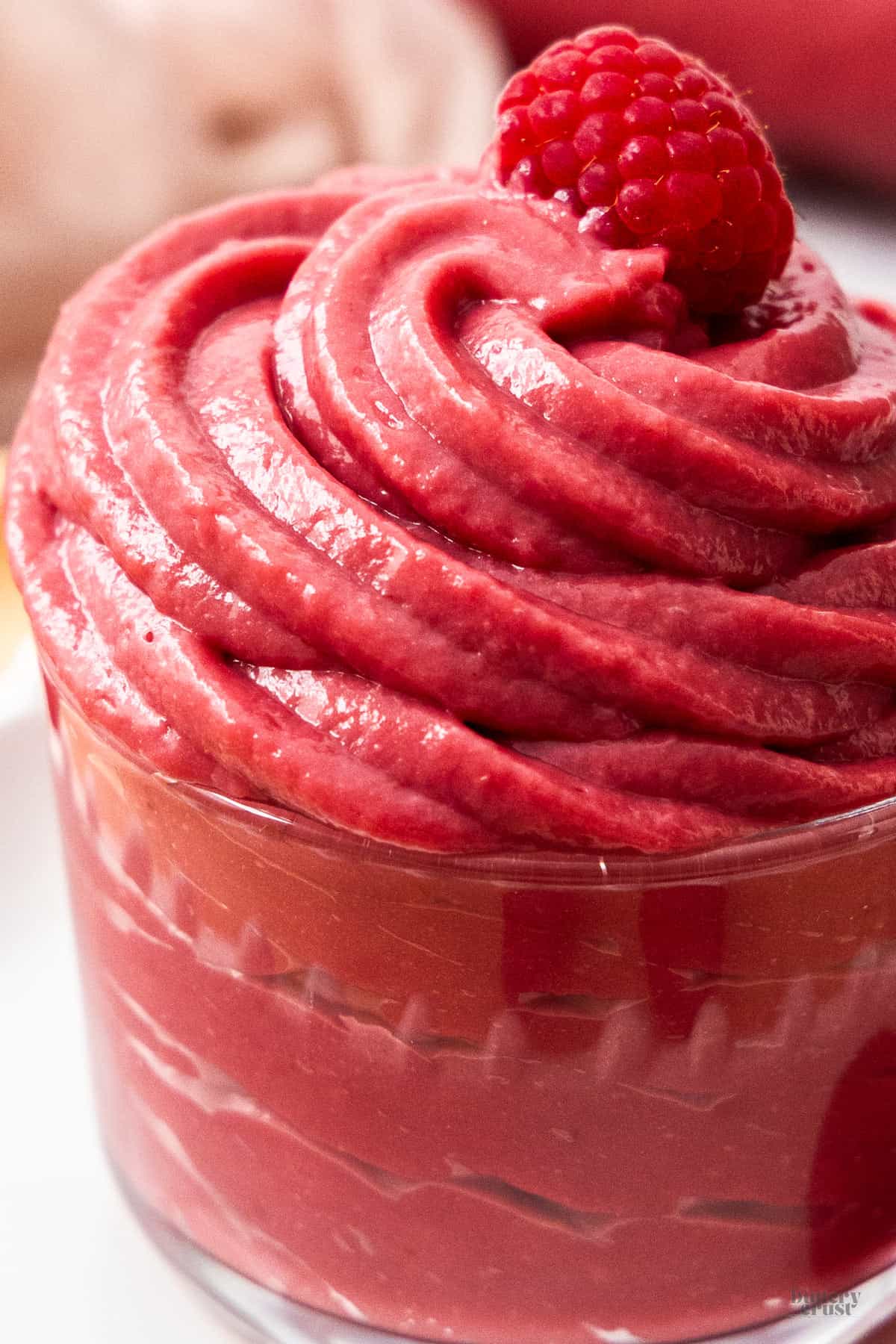 Extreme closeup of raspberry pastry cream piped into a glass.