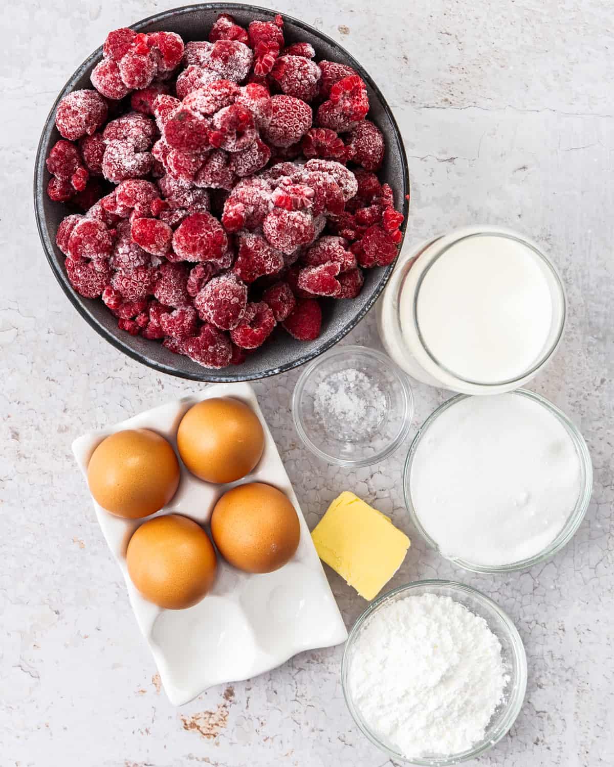 Ingredients for raspberry pastry cream on a concrete surface.