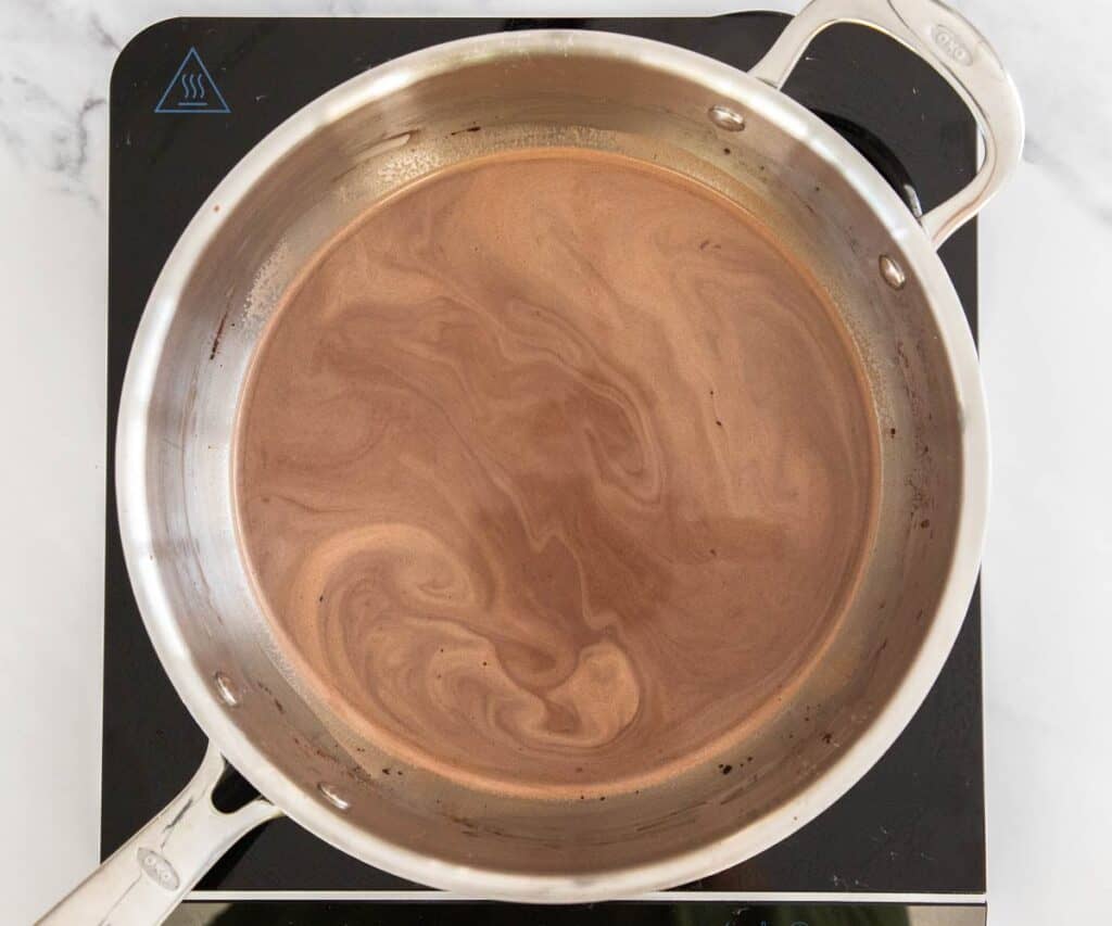 The cocoa and milk mixture being heated in a saucepan.