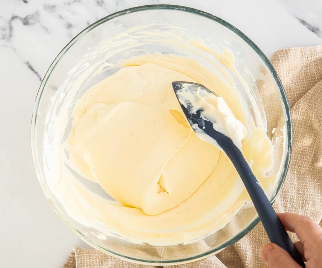 The cream being folded into the pastry cream in a mixing bowl.