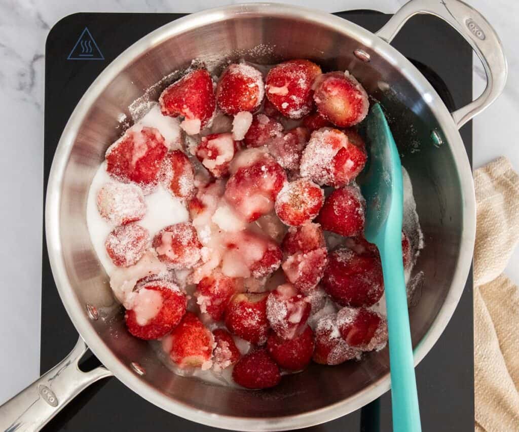 Strawberries and sugar in a saucepan.
