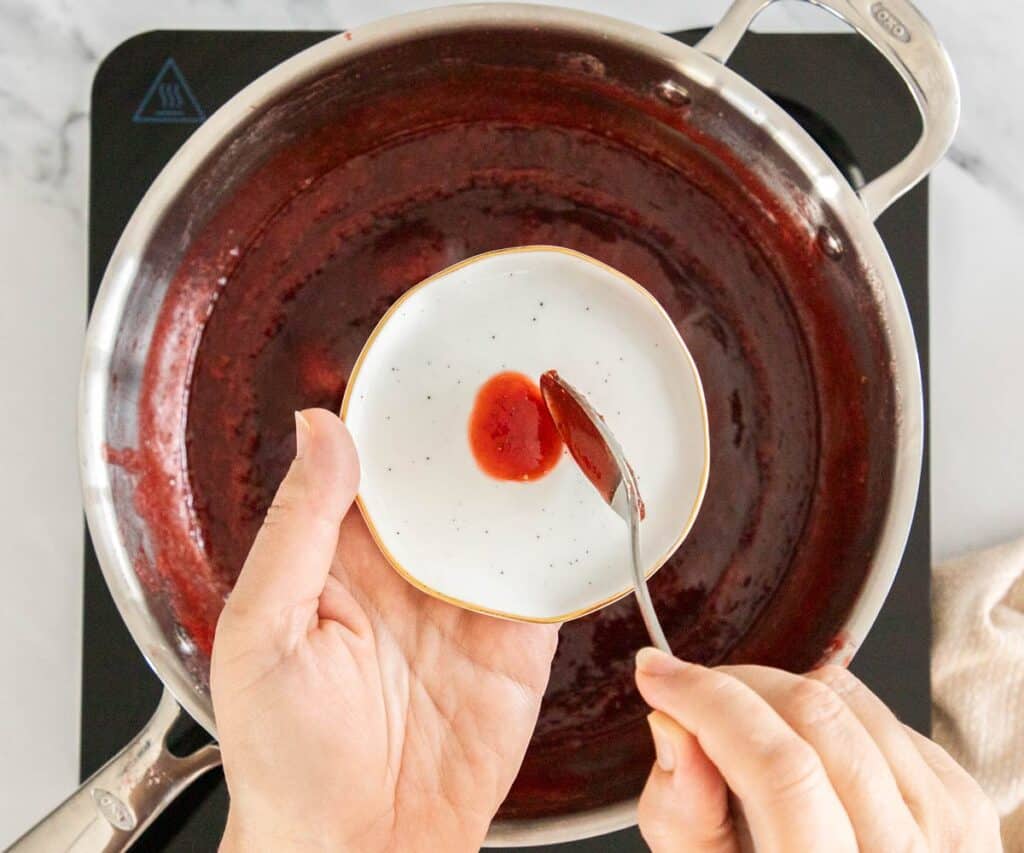 Dropping a little jam on a small plate to test consistency.