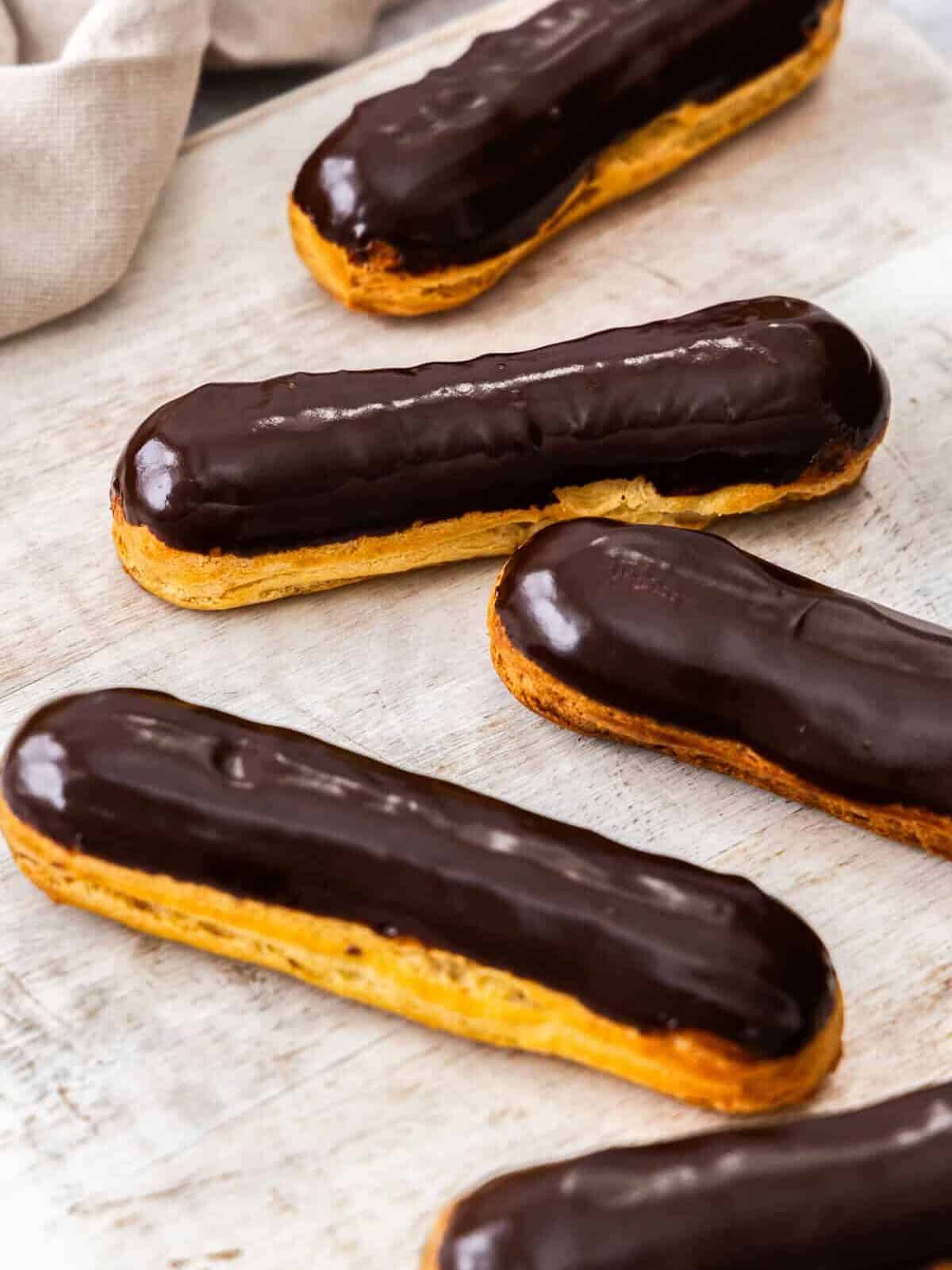 A batch of chocolate eclairs with a shiny chocolate glaze on top.