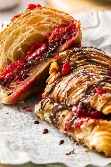 A chocolate raspberry croissant on a plate, cut in half showing the gooey filling.