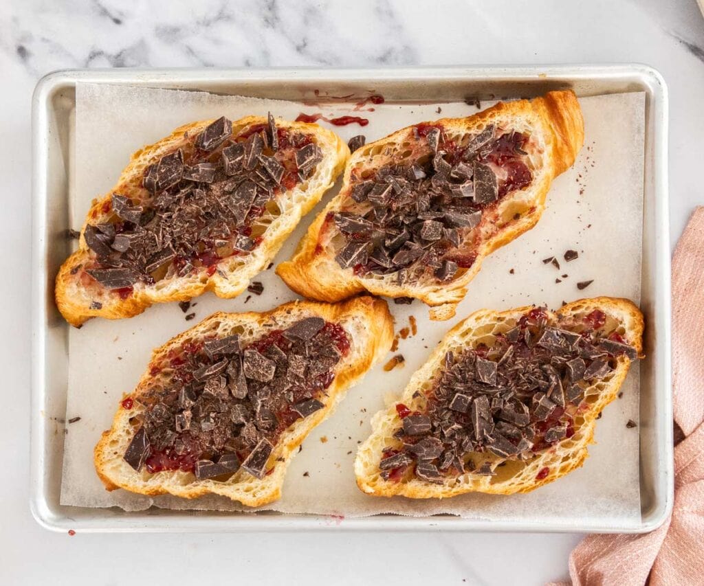 Chocolate scattered over the raspberry jam inside croissants.