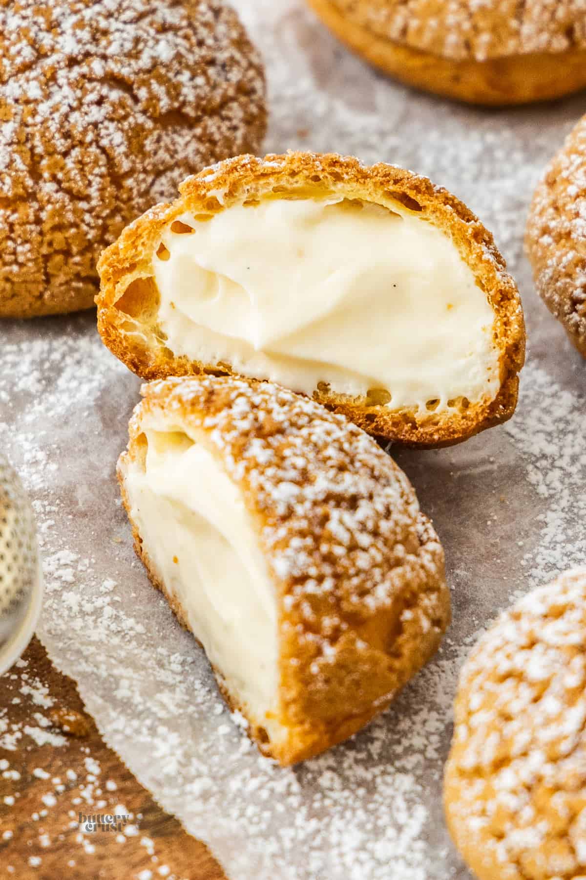 A choux a la creme cut in half and one half leaning up against the other to show the filling.