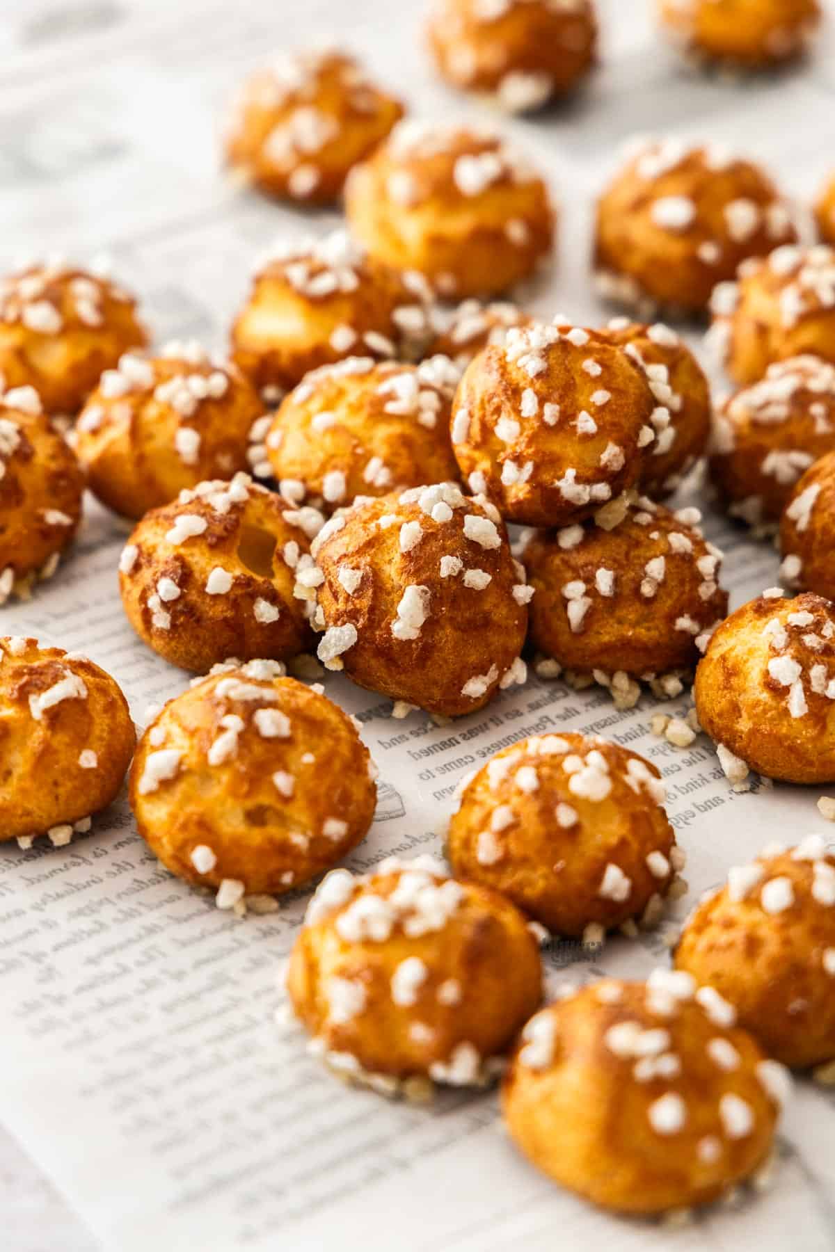A pile of chouquettes scattered over a sheet of baking paper.