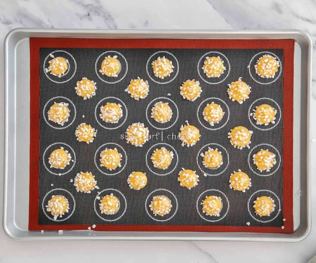 Top down view of little mounds of choux dough topped with pearl sugar.