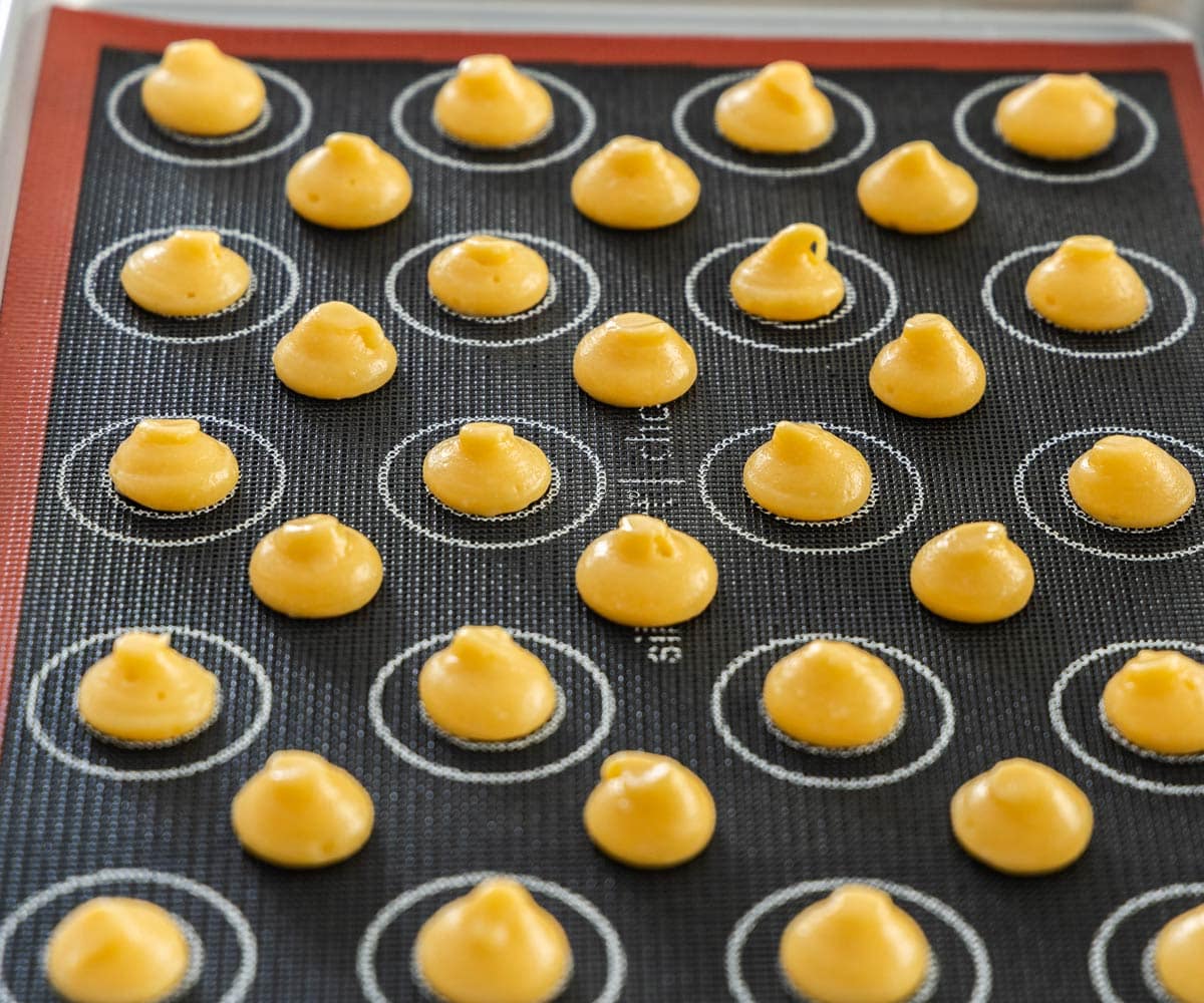 Side view of the small mounds of choux dough on a baking tray.